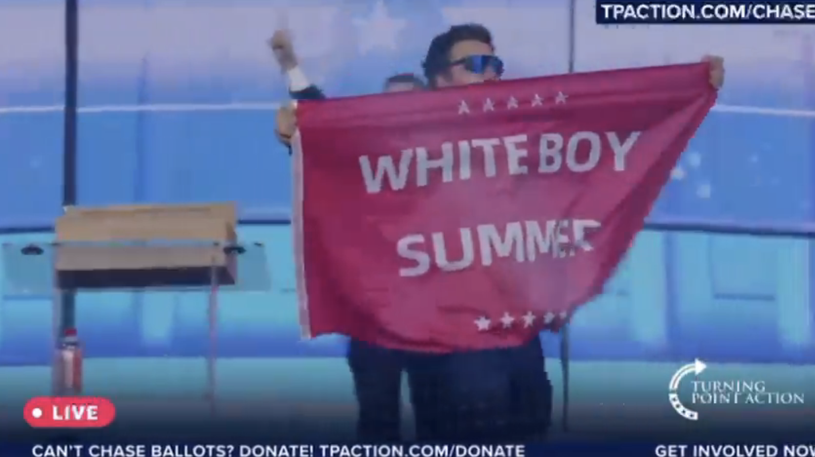 Jack Posobiec holds a banner reading &quot;Whiteboy Summer&quot; at a Turning Point Action event